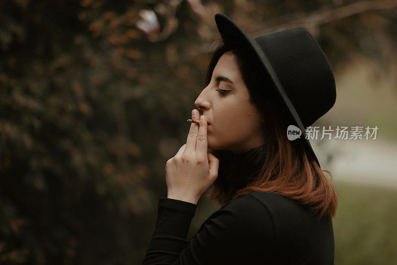 Young redhead woman profile portrait holding and smoking cigarette with eyes closed